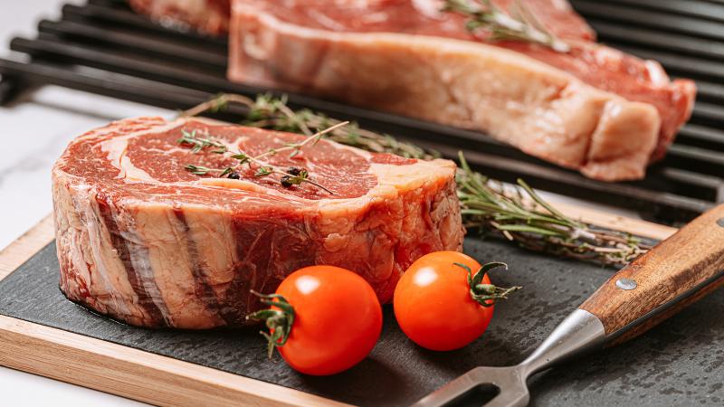 three delicious steaks ready to grill on a white marble surface